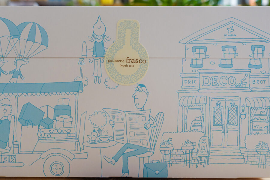 patisserie frascoで購入したカットケーキが入った箱の側面。白を基調に、スカイブルーで街並みがスケッチ風に描かれたナチュラルでやさしい印象のデザイン
