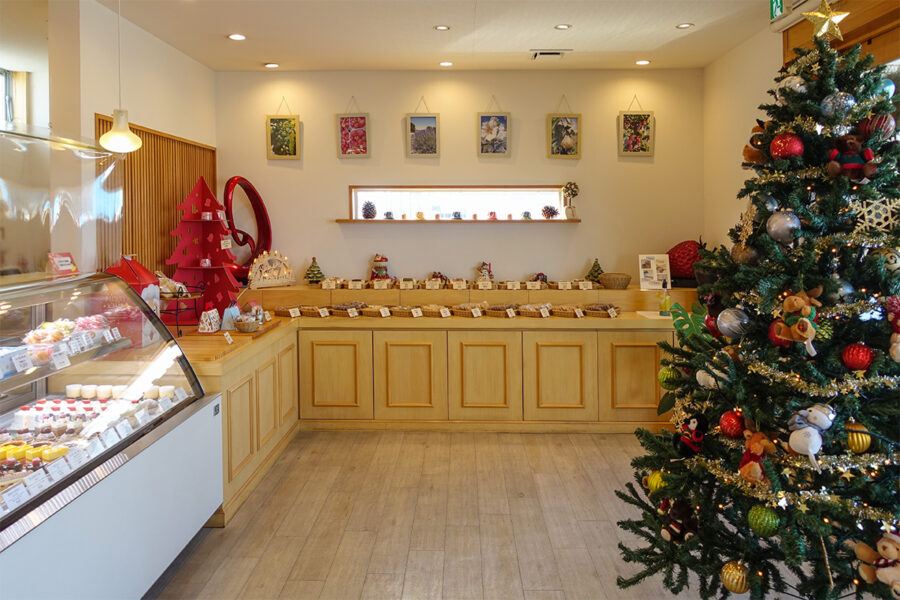 patisserie frascoの店内。木製フローリングと白い壁がナチュラルで温かみのある空間を演出。両側にショーケースとクリスマスツリーが並び、奥の棚には焼き菓子が美しく陳列されています