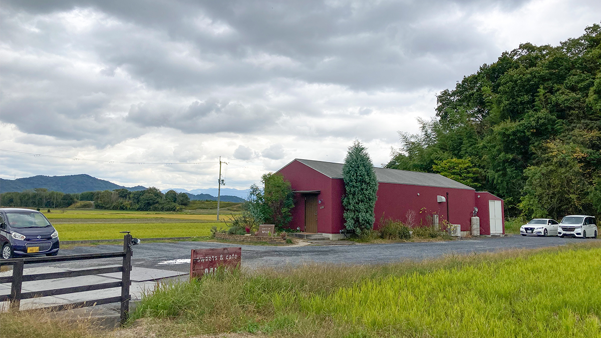 竜王町にある「sweets & Café MILK」の外観。田園風景の中に佇む赤い建物が目を引きます