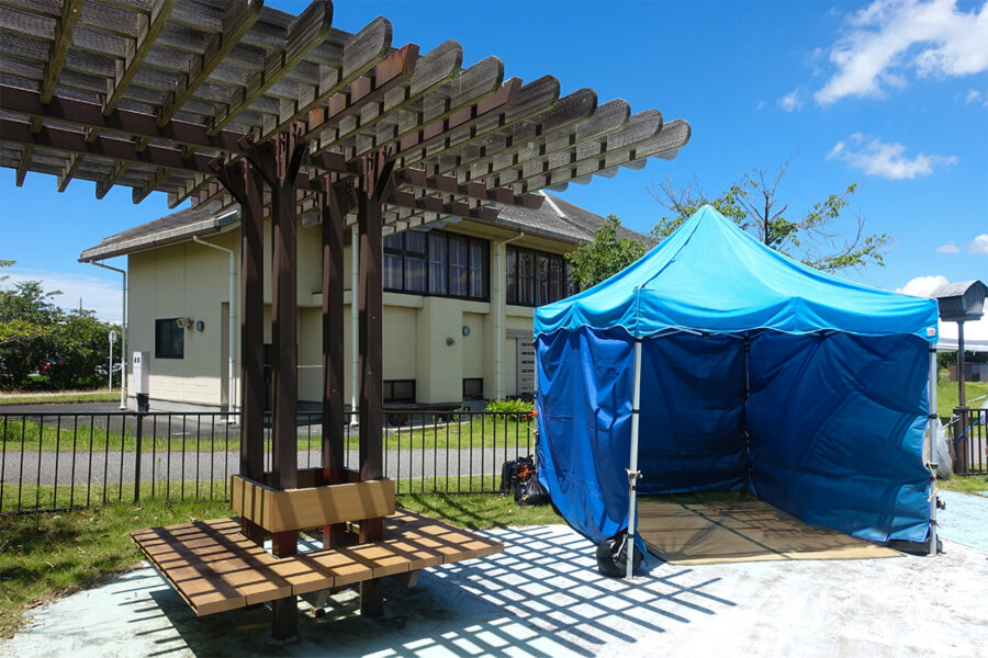 彦根市の多景公園ぞうさんプールに設置された更衣用の専用テントと、その隣に置かれたベンチの様子。利用者が休憩できるよう配慮された設備が整っています